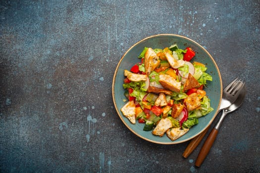 Traditional Levant dish Fattoush salad, Arab cuisine, with pita bread croutons, vegetables, herbs. Healthy Middle Eastern vegetarian salad on plate, rustic dark blue background top view, copy space.