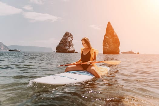 Close up shot of beautiful young caucasian woman with black hair and freckles looking at camera and smiling. Cute woman portrait in a pink bikini posing on a volcanic rock high above the sea