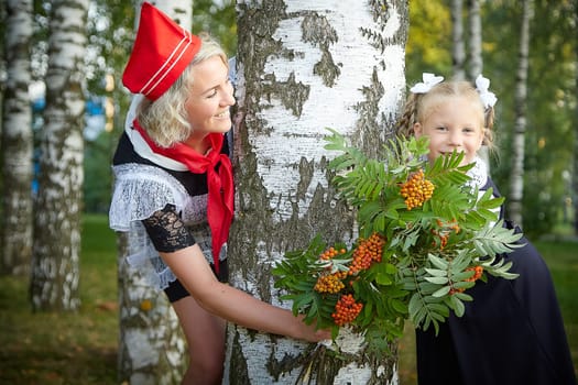 Young and adult schoolgirl on September 1, mother and daughter having fun and joy. Generations of schoolchildren of USSR and Russia. Female pioneer in red tie and October girl in modern uniform