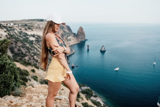 Woman travel sea. Happy tourist taking picture outdoors for memories. Woman traveler looks at the edge of the cliff on the sea bay of mountains, sharing travel adventure journey.