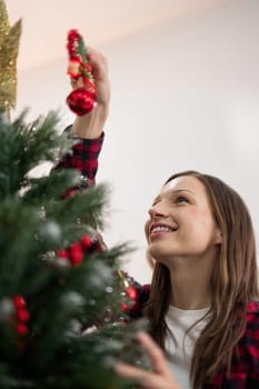 Cheerful woman decorate the christmas tree. Christmas atmosphere at cozy home interior.