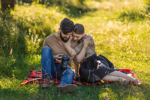 young couple relaxing in nature and looking at photos on a camera