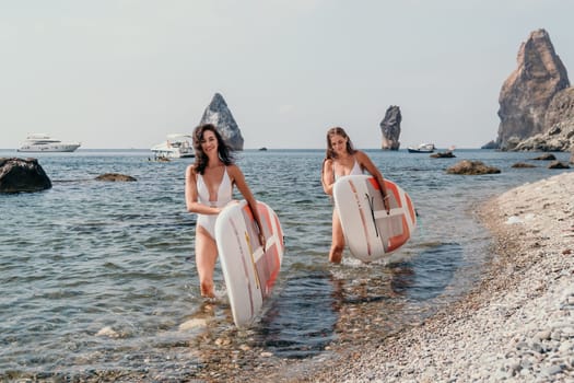 Woman sup yoga. Middle age sporty woman practising yoga pilates on paddle sup surfboard. Female stretching doing workout on sea water. Modern individual hipster outdoor summer sport activity