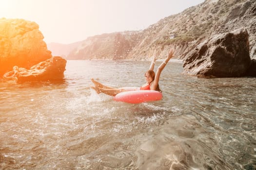 Woman summer sea. Happy woman swimming with inflatable donut on the beach in summer sunny day, surrounded by volcanic mountains. Summer vacation concept