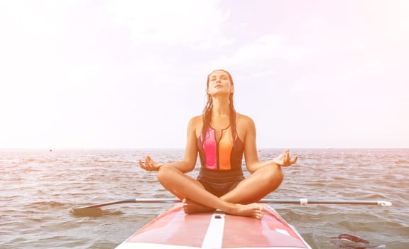 Woman sup yoga. Happy young sporty woman practising yoga pilates on paddle sup surfboard. Female stretching doing workout on sea water. Modern individual female outdoor summer sport activity