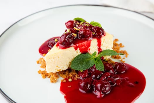 cheesecake with juicy berries and mint on a white plate