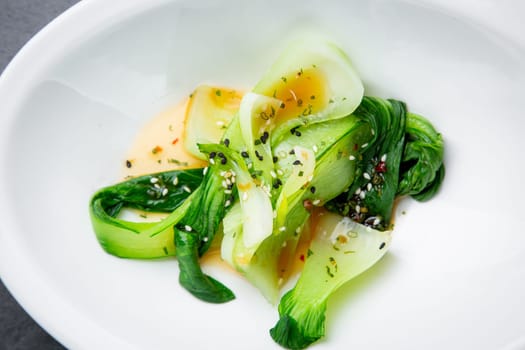 bok choy cabbage with sesame seeds and sauce in a white plate