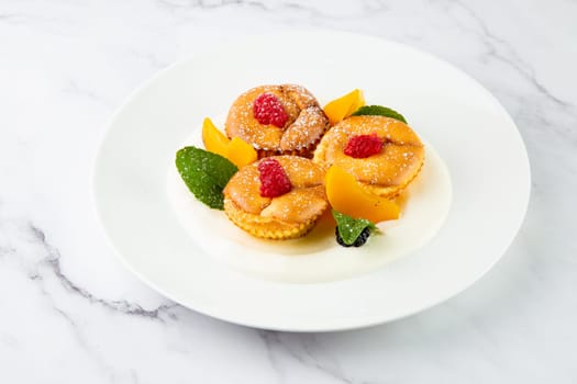 muffins with peach, raspberry, black berry and mint covered with powdered sugar