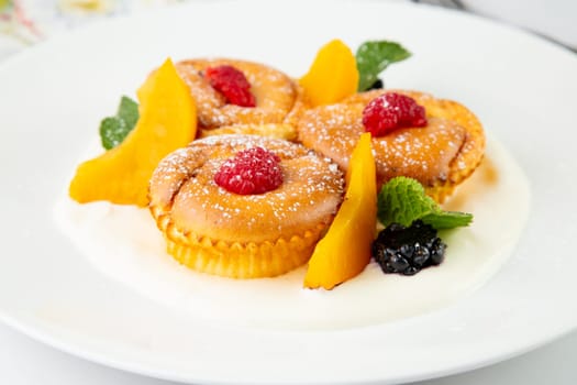 muffins with peach, raspberry, black berry and mint covered with powdered sugar