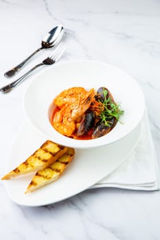 shrimp and mussels with herbs in a white plate with toasted bread