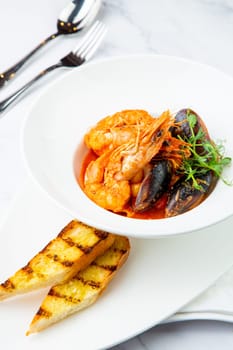 shrimp and mussels with herbs in a white plate with toasted bread