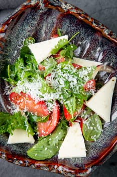 salad with herbs, tomatoes, grated cheese, sesame seeds and pieces of cheese