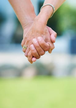 Couple, travel or holding hands for support in park, nature or outdoors on a romantic walk for love. Wellness, freedom or closeup of man with woman bonding, care or enjoying date together outside.