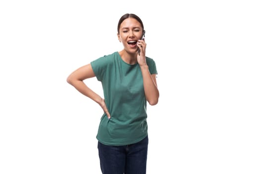 young slender european woman with a ponytail hairstyle is dressed in a green t-shirt communicates cutely on the phone.