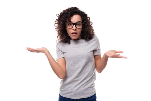 young smiling brunette curly woman dressed in a gray basic corporate color t-shirt with print mockup.