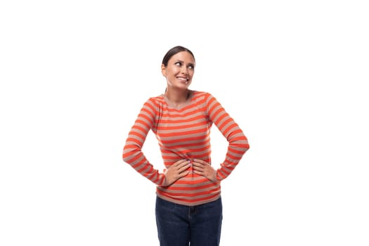 young smiling european slim woman dressed in a casual orange sweater and jeans on a white background with copy space.
