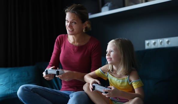 Mom and daughter hold game joysticks and play online games. Family games in game console concept