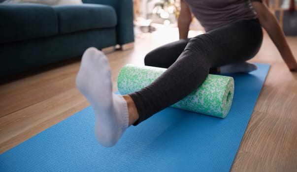 Woman massaging leg with foam roller. Body massage to relieve back pain and back muscles concept