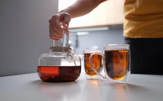 Black tea in a transparent teapot and cups. Tea brewing rules concept
