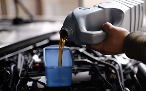 Auto mechanic pours car oil for replacement in engine. Service car in car service concept