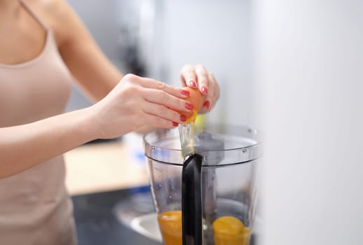 Woman adds eggs to blender for dough. Multicombine for cooking food at home concept