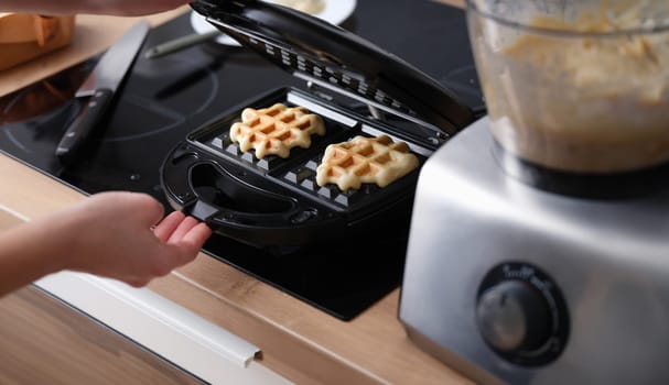 Cooking waffles in waffle iron at home. Electric waffle maker for Viennese and Belgian waffles concept