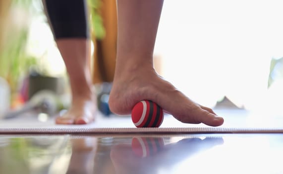 Man massages feet with small ball. Therapeutic massage of the lower extremities. Exercises for foot massage and myofascial therapy.