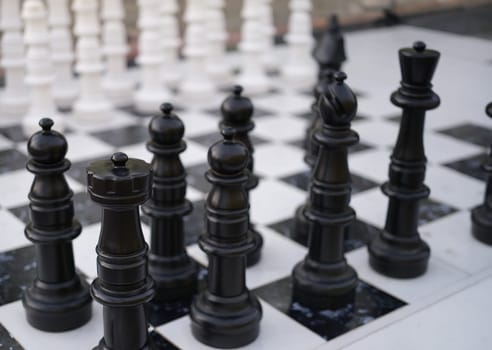 Black and white chess pieces standing on boards on street closeup. Holding chess tournaments concept