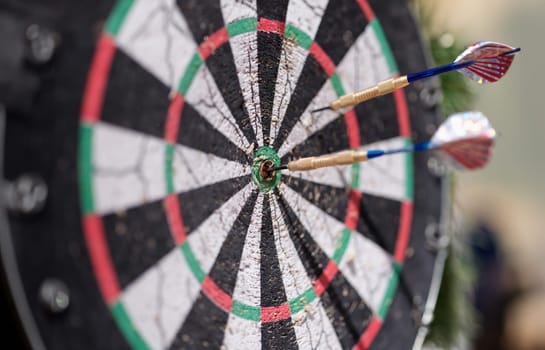 Two darts sticking out of wooden target closeup. Sports entertainment in resort concept