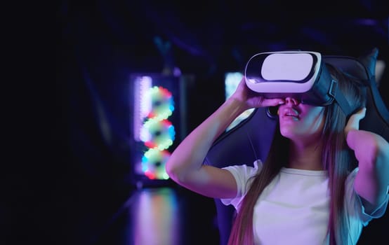 Girl gamer putting on a VR glasses in neon lighting - looking around