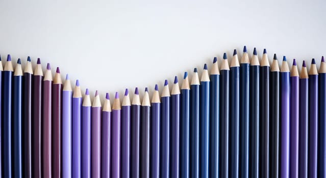Many shades of blue and purple pencils lying on white background closeup. School drawing concept