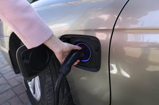 Woman hand holding charger for car closeup. Ecological fuel concept