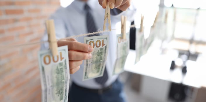 Man hanging american dollar bills on rope closeup. Laundering of money concept