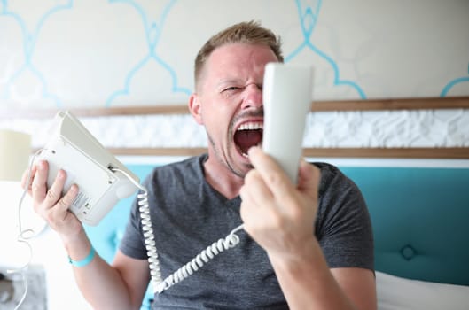 Angry man shouting into phone in hotel room. Poor hotel service concept