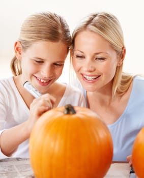 Teaching halloween traditions. a mother and daughter carving a pumpkin together