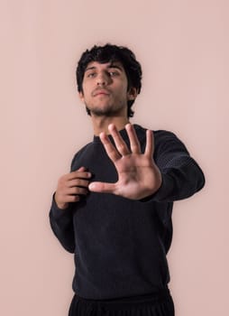 A man making a stop sign with his hands, towards the camera, in studio shot on light background