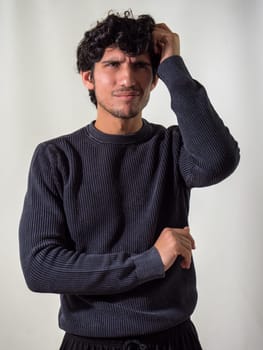 A young attractive man with curly hair is posing for a picture, with a puzzled, indecisive expression, looking up,