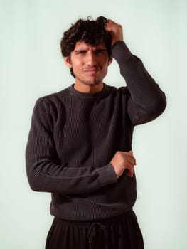 A young attractive man with curly hair is posing for a picture, with a puzzled, indecisive expression, looking up,