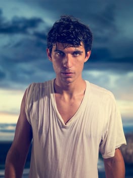 A man in a white shirt standing in front of a cloudy sky