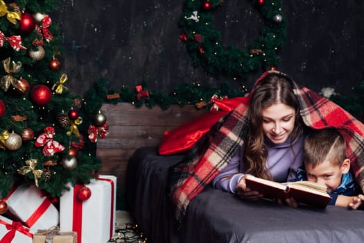 Mom with son on bed at christmas tree with gifts