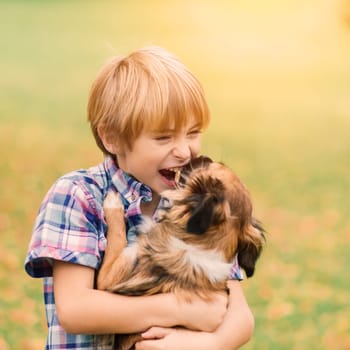 Boy hugging a dog and plyaing with in the fall, city park