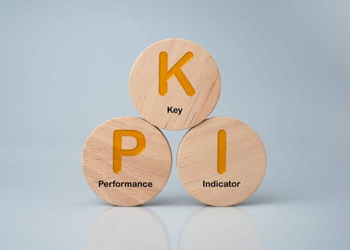 A wooden circular board printed with the abbreviation KPI on a white background represents indicators and KPIs to improve organizational performance, marketing, corporate financial strategies.