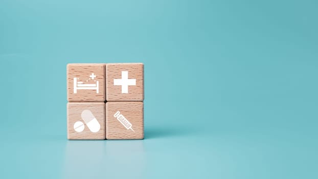 Wooden blocks with medical symbol icons on blue background representing health concept with treatment and medicine.