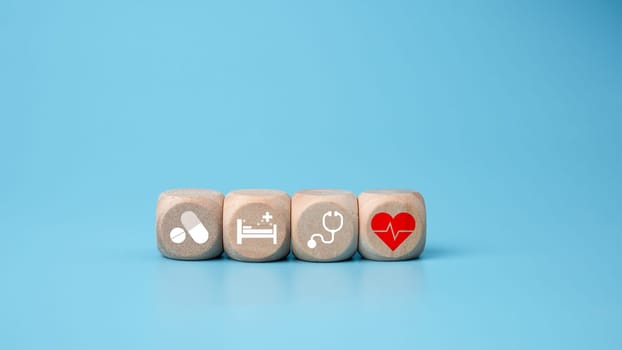 Wooden blocks with medical symbol icons on blue background representing health concept with treatment and medicine.