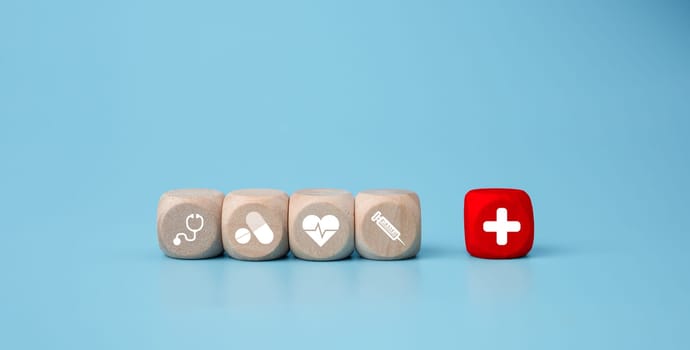 Wooden blocks with medical symbol icons on blue background representing health concept with treatment and medicine.