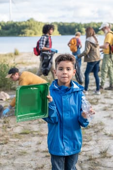 boy collects garbage plastic waste on the shore of a lake together with his volunteer friends, the concept of educating a new generation and cleaning the environment, ecology, High quality photo