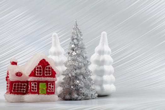 Christmas or New Year background with silver snowy fir tree and red toy house. Bright festive background.