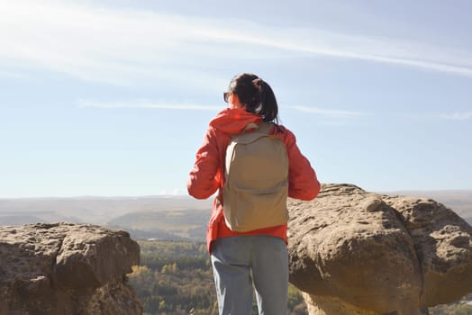 Active young woman with backpack hiking in the mountains enjoying panoramic views