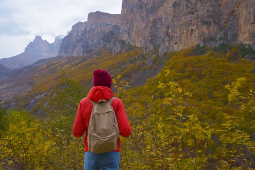 Brunette woman with a backpack on her back outdoors exploring the Caucasus Mountains in Russia, traveling, lifestyle, hiking, active autumn holidays, hiking.