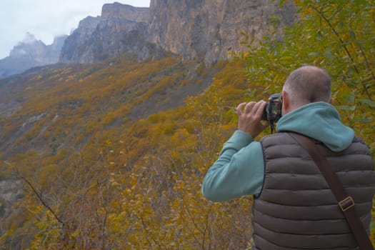 a tourist takes pictures of a beautiful autumn mountain landscape using a camera.